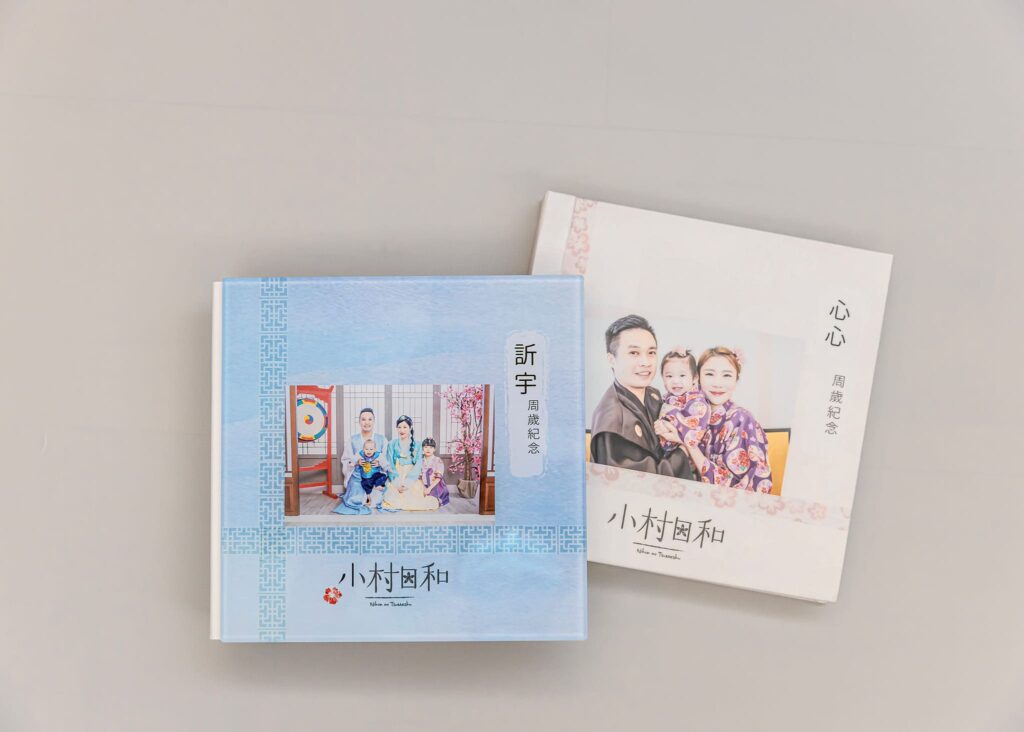 兩本精美的抓周紀念相簿，封面印有家庭合照，紀錄寶寶成長的珍貴時刻，是值得珍藏的美好回憶。