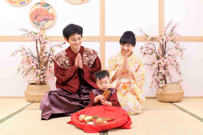 寶寶與父母身穿日式和服,在榻榻米攝影棚中進行抓周儀式,桌上擺放傳統抓周道具,充滿和風氛圍。