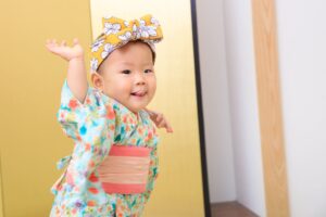 可愛的寶寶穿著日式和服,搭配大蝴蝶結頭飾,開心地擺出俏皮姿勢,拍攝於抓周攝影棚內。