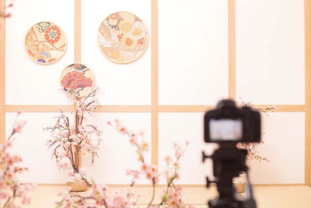 日式抓周攝影場景佈置,榻榻米空間搭配和風圓盤與櫻花裝飾,攝影機架設中,記錄抓周拍攝的準備畫面