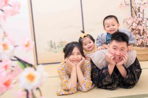 日式場景中,一家四口穿著傳統和風服飾溫馨合影,寶寶與哥哥坐在爸爸肩上開心微笑,滿周歲紀念照。
