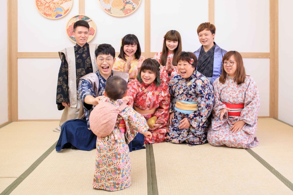 寶寶抓周儀式現場,家人穿著傳統和服圍坐拍手迎接寶寶走向家人