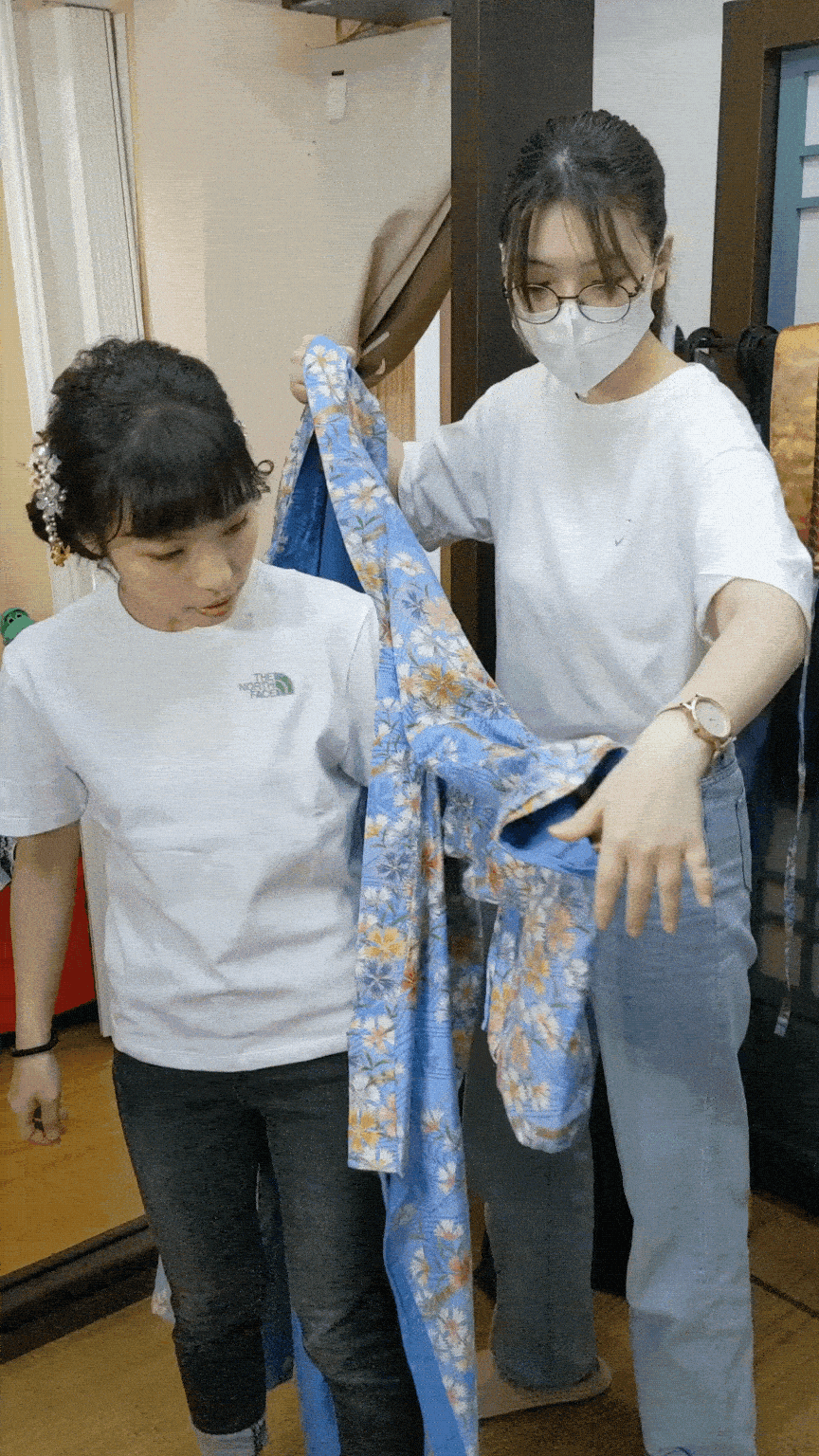 穿和服的動態過程展示，專業工作人員正在協助顧客穿著和服，呈現細緻服務與穿搭過程的互動畫面。