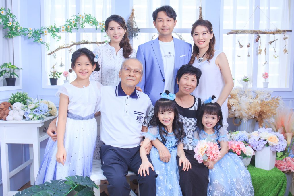 一家三代身穿白色與藍色系服裝，在充滿溫馨感的攝影棚內拍攝現代風格家庭合照。