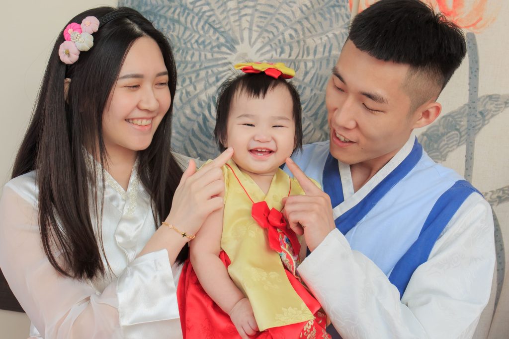 父母與寶寶身穿韓服互動玩耍，孩子開心露出笑容，展現親子間的溫暖連結。