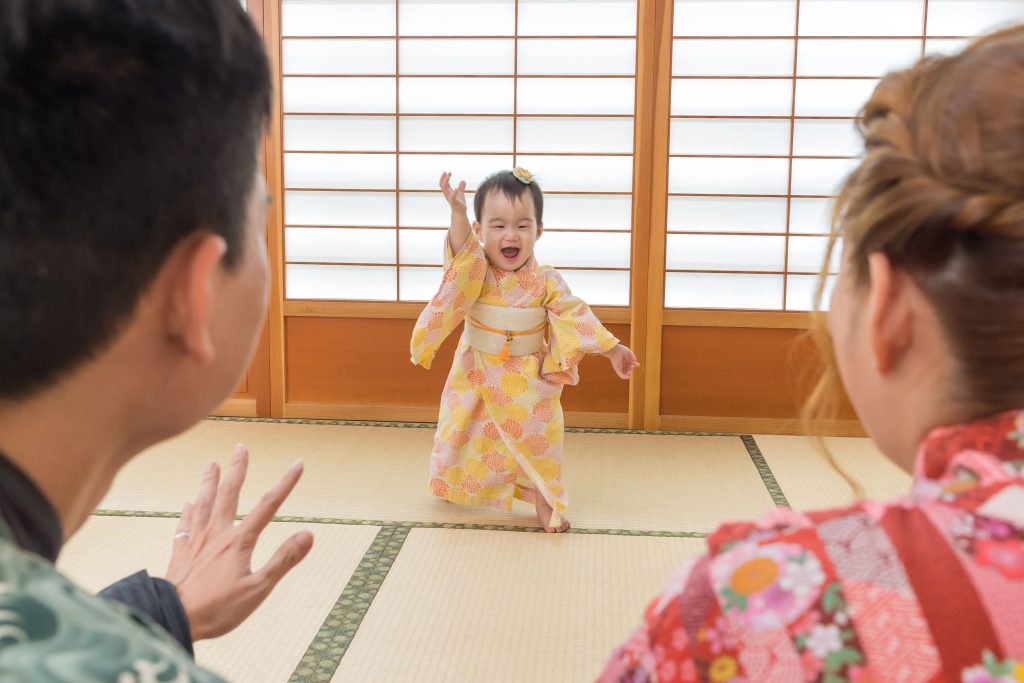 穿著和服的寶寶在榻榻米上開心奔向爸媽，記錄珍貴的親子互動畫面。