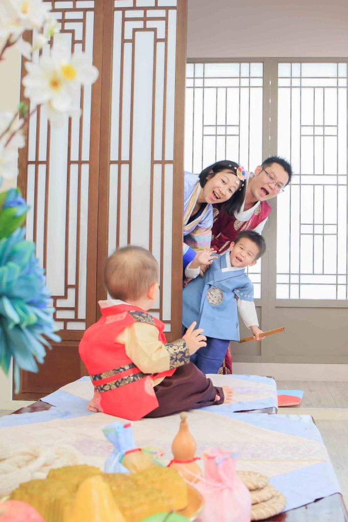 一家人在溫馨場景中陪伴寶寶參與抓周儀式,形成現代結合傳統家庭式的歡樂氛圍。