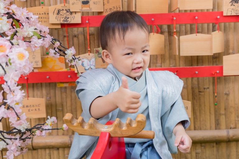 寶寶抓周儀式現場，小男嬰穿日式和風服裝，在抓周場景中開心比讚互動