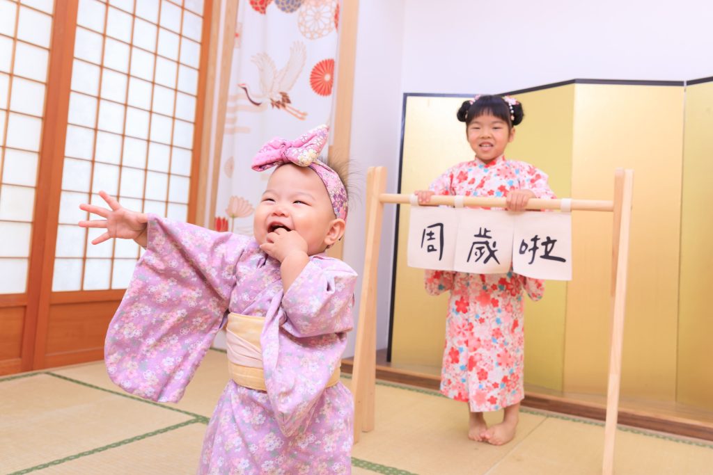 寶寶抓周儀式歡樂瞬間,小女孩穿粉色和服開心揮手,搭配日式場景與祝福氛圍